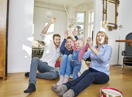 Glückliche Familie mit spielendem Mädchen im Wohnzimmer - FMKF03650