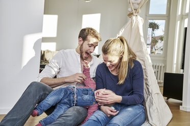 Glückliche Familie mit spielendem Mädchen zu Hause - FMKF03653