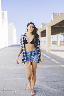 Junge hübsche Frau in Strandkleidung, die auf der Straße geht - GIOF02353