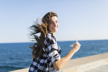 Young pretty woman wearing beach wear wlaking by the sea - GIOF02366