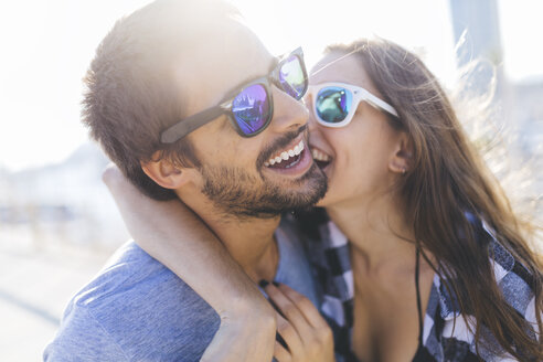 Glückliches junges Paar beim Spaziergang am Hafen, küssend - GIOF02378