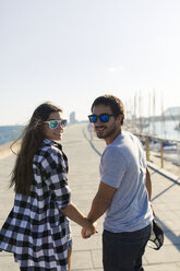 Happy young couple walking at the harbour - GIOF02380