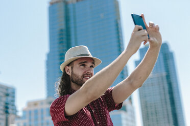 USA, New York City, Mann macht ein Selfie vor Wolkenkratzern - GIOF02400