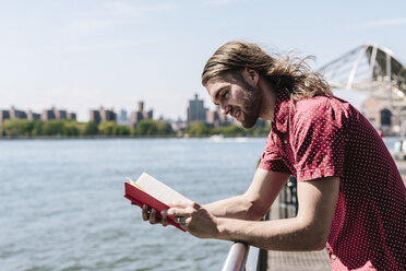 USA, New York City, Mann liest Buch am Hafen - GIOF02414