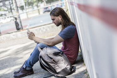 Mann sitzt und schaut auf ein Tablet - GIOF02424