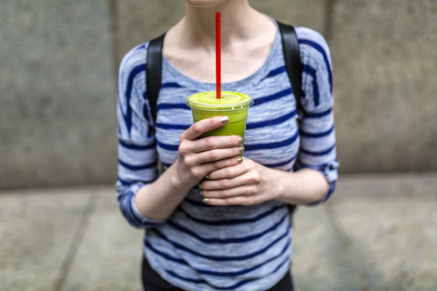 Frau hält einen Smoothie im Freien, lizenzfreies Stockfoto