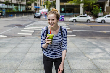 USA, New York City, lauging young woman with a smoothie in Manhattan - GIOF02439