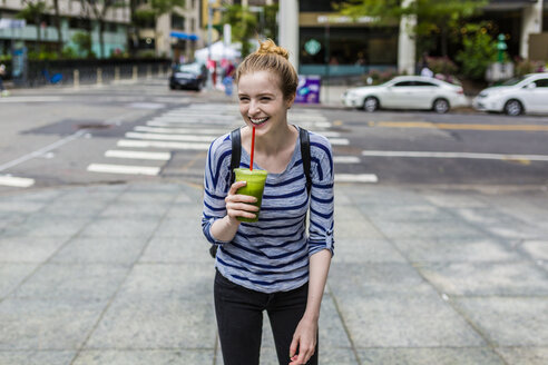 USA, New York City, lachende junge Frau mit einem Smoothie in Manhattan - GIOF02439