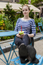 Junge Frau macht eine Pause und trinkt einen Smoothie im Freien - GIOF02445