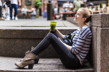 USA, New York City, lächelnde Frau, die eine Pause macht und einen Smoothie in Manhattan trinkt - GIOF02453