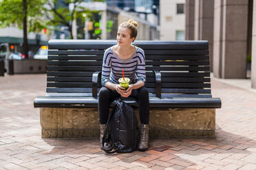 USA, New York City, woman sitting on a bench drinking a smoothie in Manhattan - GIOF02458