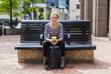 USA, New York City, portrait of woman sitting on a bench drinking a smoothie in Manhattan - GIOF02459