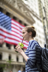 USA, New York City, Frau trinkt einen Smoothie vor der New York Stock Exchange - GIOF02465