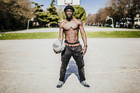 Porträt eines Basketballspielers mit freiem Oberkörper auf dem Spielfeld, lizenzfreies Stockfoto