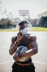 Barechested basketball player on court smoking a joint - GIOF02476