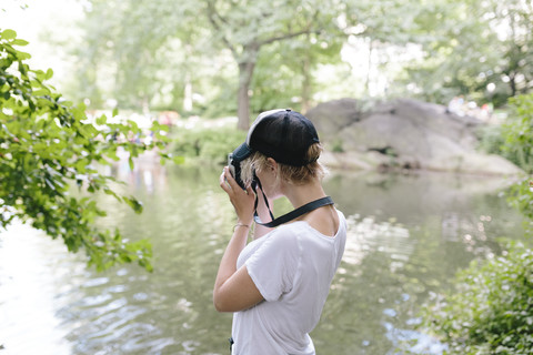 Junge Frau mit einer alten Kamera, die im Park fotografiert, lizenzfreies Stockfoto
