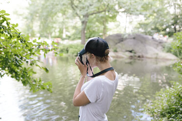 Junge Frau mit einer alten Kamera, die im Park fotografiert - BOYF00727