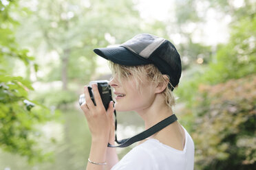 Junge Frau mit einer alten Kamera, die im Park fotografiert - BOYF00729