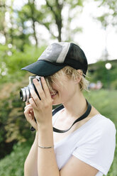 Young woman with a vintage camera taking pictures in park - BOYF00730