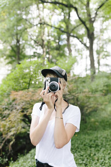 Junge Frau mit einer alten Kamera, die im Park fotografiert - BOYF00731