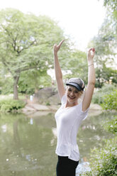 Porträt einer glücklichen jungen Frau am Seeufer im Park - BOYF00741