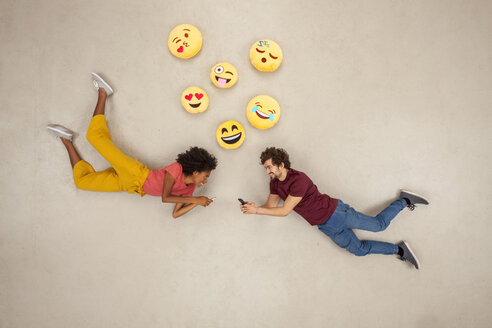 Happy couple texting on their smart phones, sending emojies - BAEF01237