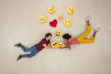 Glückliches Paar, das sich mit Emojis über dem Kopf verliebt - BAEF01239
