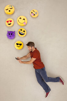 Mann chattet mit seinem Smartphone und sendet Emojis - BAEF01296