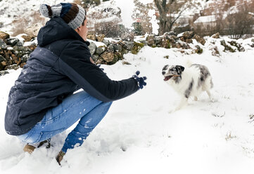 Junger Mann spielt mit seinem Hund im Schnee - MGOF03075