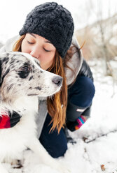 Junge Frau küsst ihren Hund im Schnee - MGOF03078