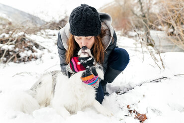 Junge Frau küsst ihren Hund im Schnee - MGOF03079