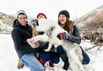 Drei Freunde haben Spaß daran, ein Selfie mit einem Hund im Schnee zu machen - MGOF03087