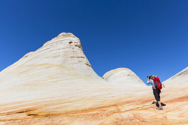 USA, Utah, Canaan Mountain, Hildale, hiking trip towards White Domes and Water Canyon, woman taking pictures of colored sandstone rocks - FOF09073