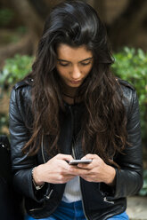 Junge Frau benutzt ein Mobiltelefon im Freien - KKAF00521