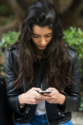 Young woman using a cell phone outdoors - KKAF00521