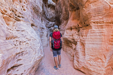 USA, Nevada, Valley of Fire State Park, sandstone and limestone rocks, tourist in narrow passageway - FOF09096