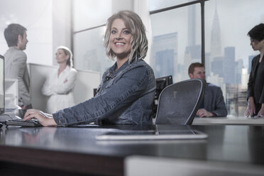 Lächelnde Frau am Schreibtisch in einem städtischen Büro - ZEF13175
