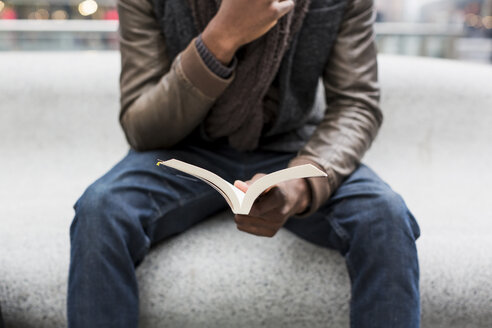 Junger Mann sitzt auf einer Bank und liest ein Buch, Teilansicht - MAUF00992