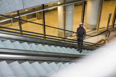 Junger Mann steht auf einer Rolltreppe und schaut sich um - MAUF00995