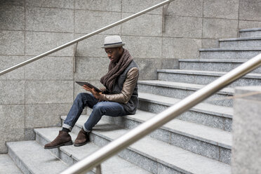 Mann sitzt auf einer Treppe und benutzt ein Tablet - MAUF00998