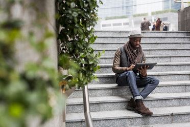 Mann sitzt auf einer Treppe und benutzt ein Tablet - MAUF00999