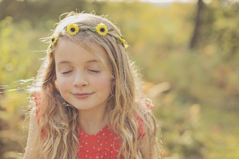 Porträt eines entspannten kleinen Mädchens mit geschlossenen Augen und Blumenkranz, lizenzfreies Stockfoto