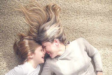 Mutter und kleine Tochter liegen auf dem Teppich und haben Spaß - RTBF00752