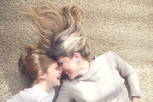 Mother and little daughter lying on carpet having fun - RTBF00752