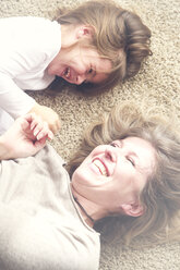 Mutter und kleine Tochter liegen auf dem Teppich und haben Spaß - RTBF00755