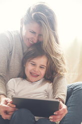 Mother and little daughter using tablet at home - RTBF00760