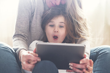Porträt eines staunenden kleinen Mädchens, das mit seiner Mutter ein Tablet benutzt - RTBF00762
