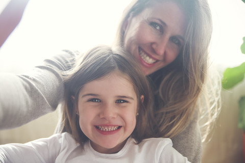 Porträt von Mutter und kleiner Tochter, die ein Selfie zu Hause machen, lizenzfreies Stockfoto