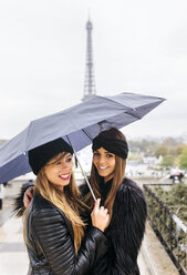 Frankreich, Paris, zwei junge Frauen, die einen Regenschirm halten, mit dem Eiffelturm im Hintergrund - MGOF03090