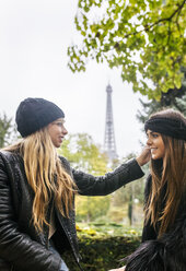 Frankreich, Paris, zwei beste Freunde sitzen in einem Park mit dem Eiffelturm im Hintergrund - MGOF03091